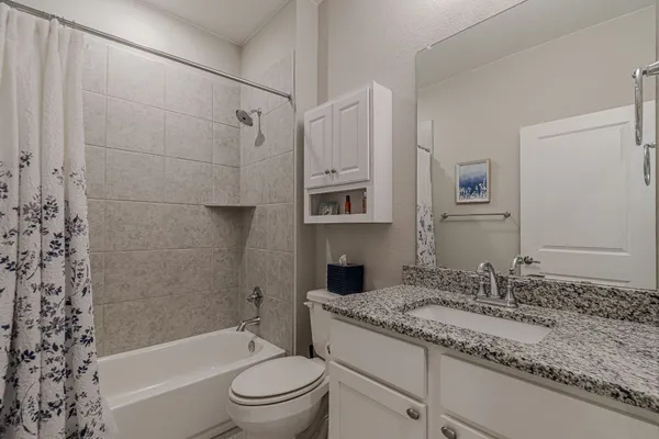 a bathroom with a granite countertop sink a toilet and shower