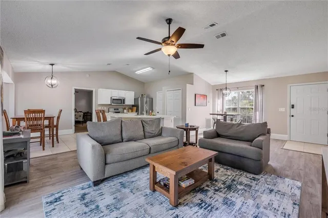 a living room with furniture kitchen view and a chandelier