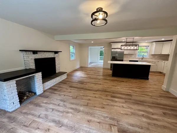 a view of a room with kitchen island stainless steel appliances wooden floor and living room view