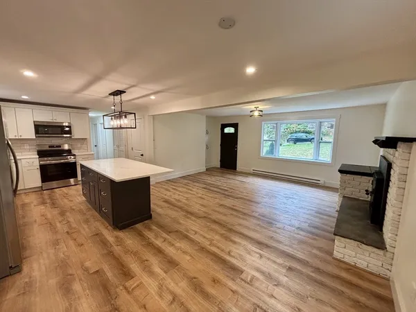 a large room with kitchen island wooden floors and stainless steel appliances