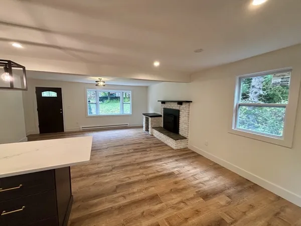 a view of an empty room with window and wooden floor