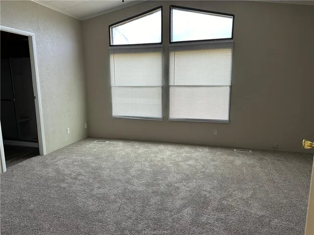 an empty room with a window and a fan