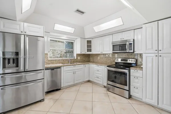 a kitchen with granite countertop cabinets stainless steel appliances and a counter space