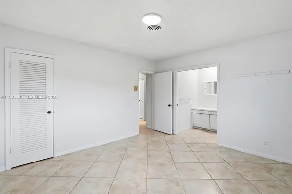 a view of an empty room with closet and a window