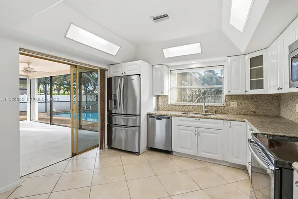 a kitchen with a stove a sink dishwasher a refrigerator and white cabinets with wooden floor