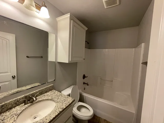 a bathroom with a granite countertop sink toilet and shower