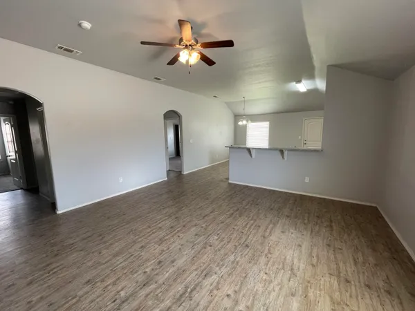 a view of a livingroom with a ceiling fan wooden floor and a ceiling fan