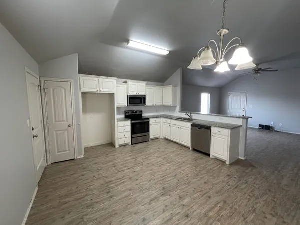 a large kitchen with kitchen island a stove a sink dishwasher a refrigerator and a fireplace with wooden floor