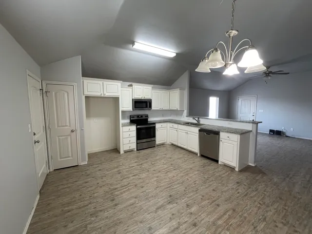 a large kitchen with kitchen island a stove a sink dishwasher a refrigerator and a fireplace with wooden floor