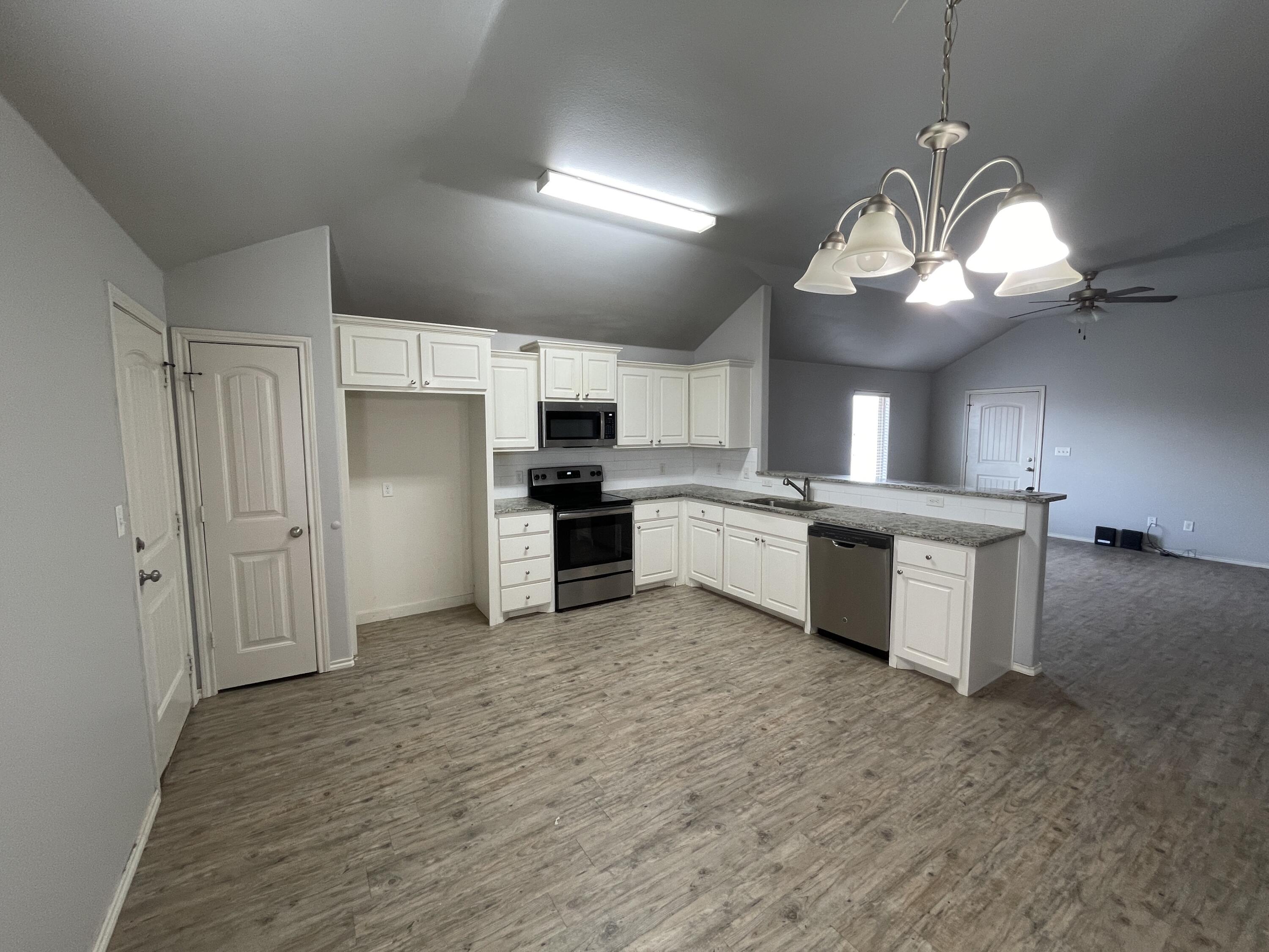 1012 Preston Trail Wolfforth, TX 79382 - Photo 6 of 21 a large kitchen with kitchen island a stove a sink dishwasher a refrigerator and a fireplace with wooden floor