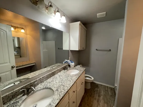 a bathroom with a granite countertop sink a large mirror a toilet and vanity