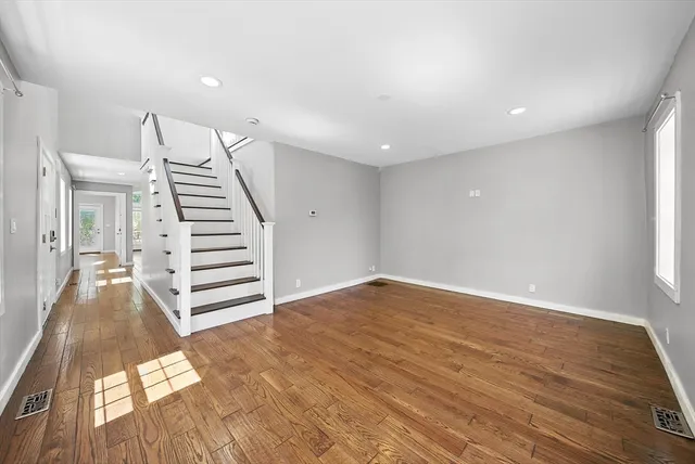 a view of an empty room with wooden floor and stairs