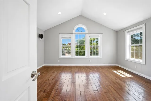 an empty room with wooden floor and windows