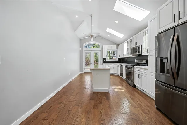 a large kitchen with cabinets wooden floor and stainless steel appliances