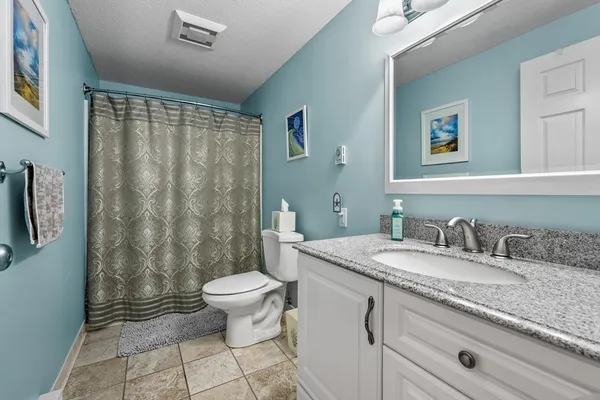a bathroom with a granite countertop sink a toilet and a mirror