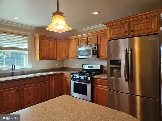 a view of a refrigerator in kitchen with stainless steel appliances wooden floor