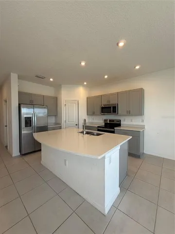 a large white kitchen with stainless steel appliances granite countertop a sink and a stove
