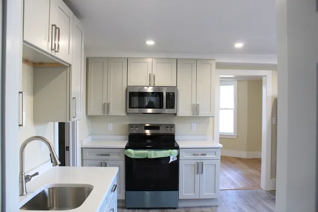 a kitchen with stainless steel appliances granite countertop a stove a sink and a microwave