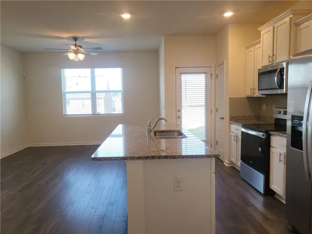a kitchen with kitchen island granite countertop a stove top oven a sink and dishwasher with wooden floor