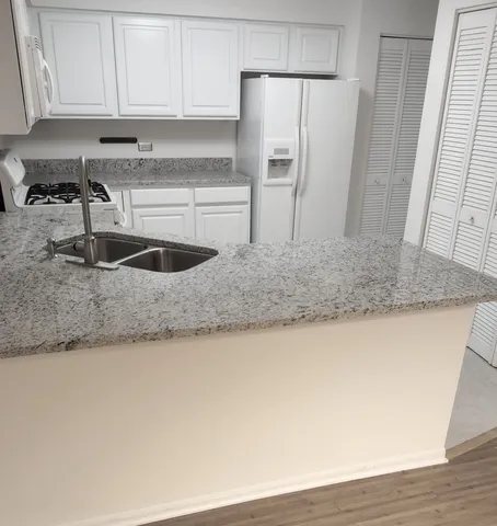 a kitchen with stainless steel appliances granite countertop a sink a refrigerator a counter top space and cabinets