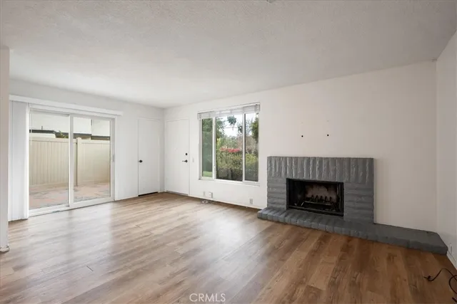 an empty room with wooden floor fireplace and windows