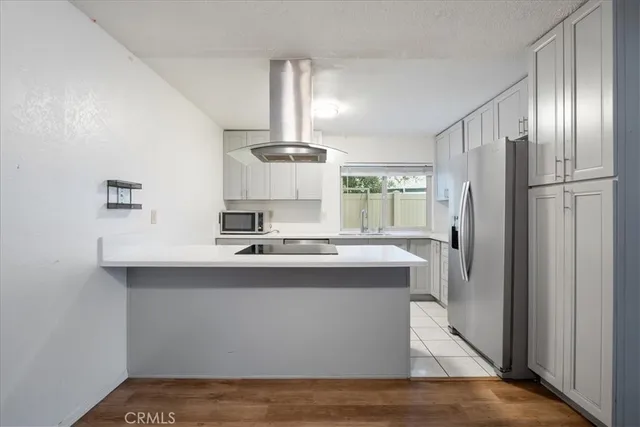 a kitchen with kitchen island stainless steel appliances a sink stove refrigerator and cabinets