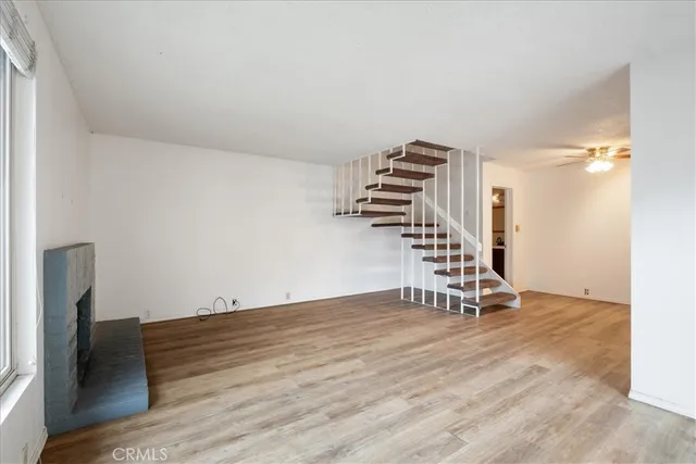 a view of an empty room with wooden floor and stairs