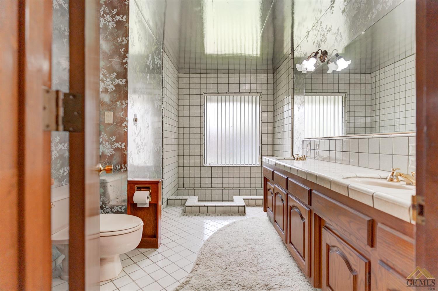 Undisclosed Address Bakersfield, CA 93309 - Photo 33 of 38 a bathroom with a granite countertop toilet a sink a mirror a shower and a bathtub