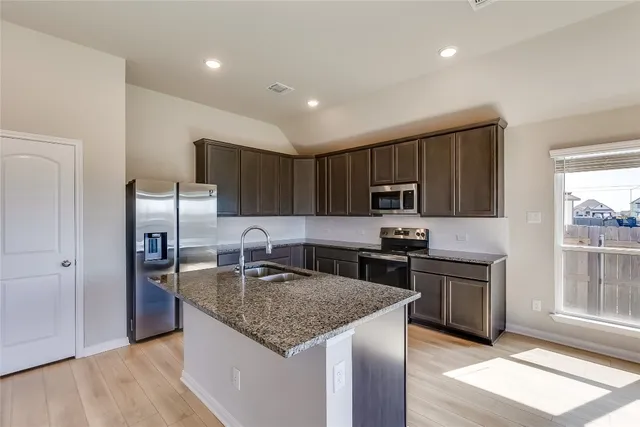 a kitchen with stainless steel appliances granite countertop a sink stove microwave and refrigerator