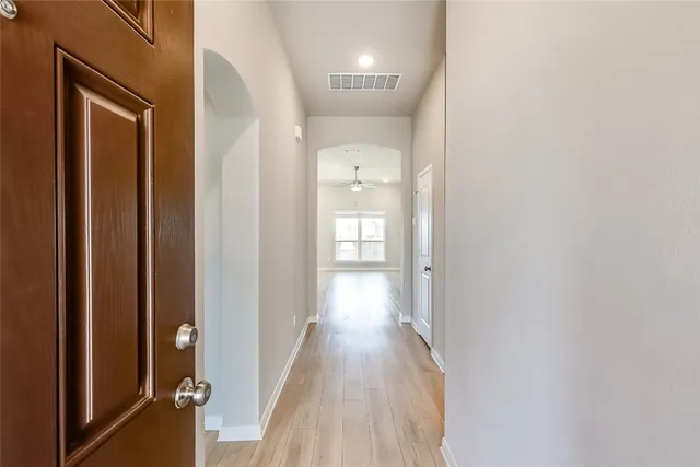 a view of a hallway with wooden floor and a bathroom