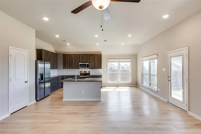 a large kitchen with a center island wooden floor stainless steel appliances and windows
