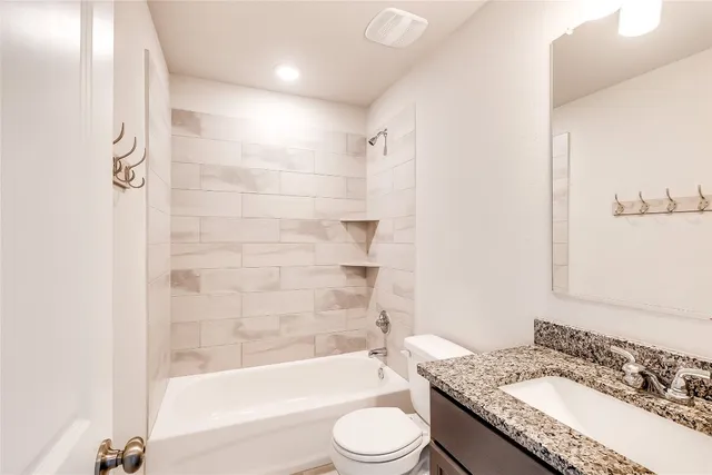 a bathroom with a granite countertop sink toilet bathtub and shower