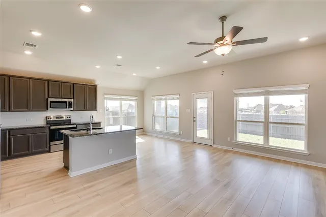 a large kitchen with stainless steel appliances granite countertop a stove and a wooden floors