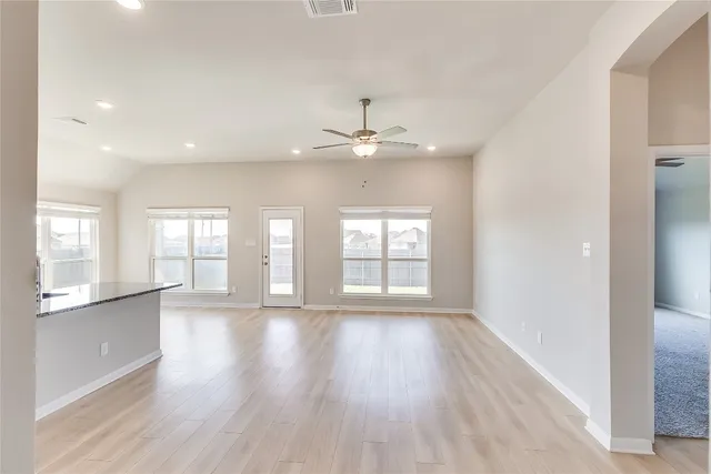 a view of an empty room with a window and wooden floor