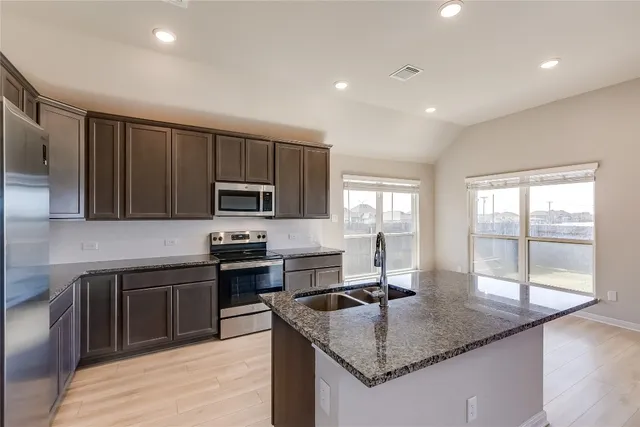 a kitchen with stainless steel appliances granite countertop a sink stove and refrigerator
