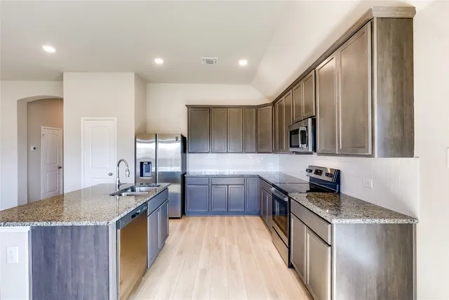 a kitchen with kitchen island granite countertop a sink stove and refrigerator