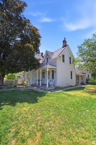 310 South 300 West Payson, UT 84651 - Photo 7 of 42 Traditional-style property featuring a covered front porch with white columns, light-colored siding, multiple gables, and a prominent brick chimney