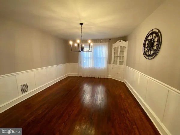 a view of an empty room with wooden floor and chandelier