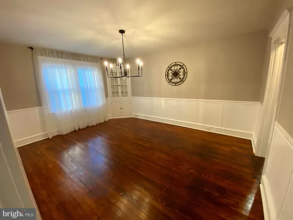 a view of a big room with wooden floor chandelier and windows