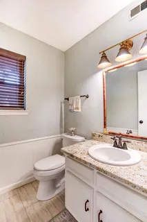 a bathroom with a granite countertop sink a toilet and a mirror