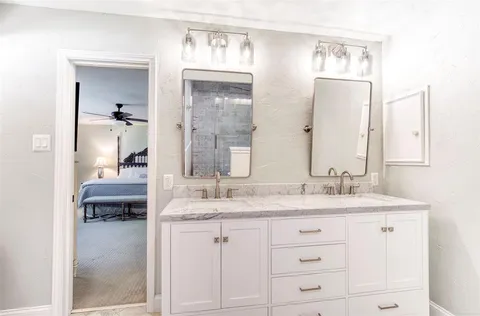 a en suite bathroom with a granite countertop sink and a mirror