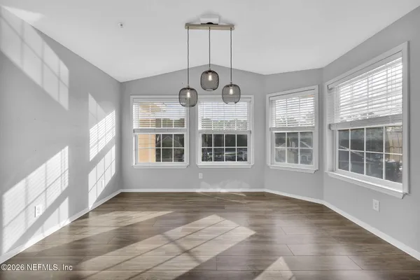 an empty room with wooden floor cabinet and windows
