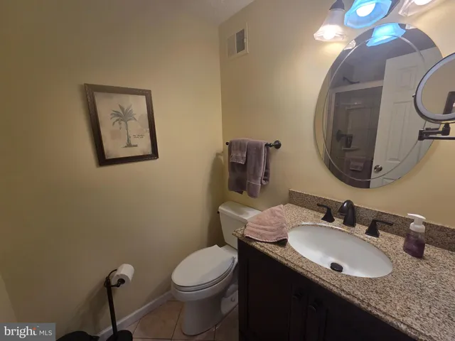 a bathroom with a granite countertop toilet a sink and a mirror