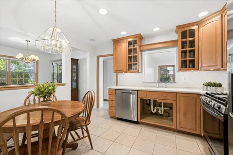 a kitchen with stainless steel appliances granite countertop a stove top oven a sink dishwasher a dining table and chairs with wooden floor