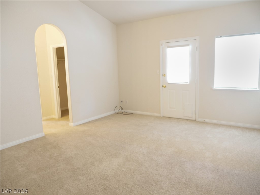 Spacious primary bedroom with light colored carpet and door to backyard