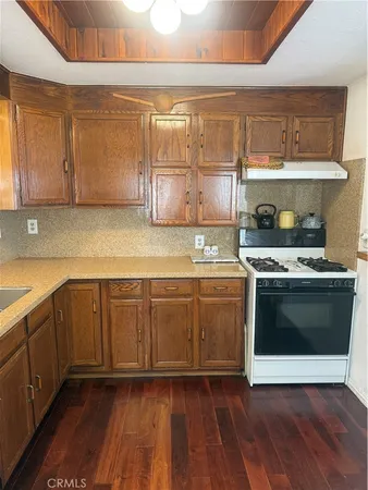 a kitchen with stainless steel appliances granite countertop a sink a stove a refrigerator with grey cabinets and wooden floor