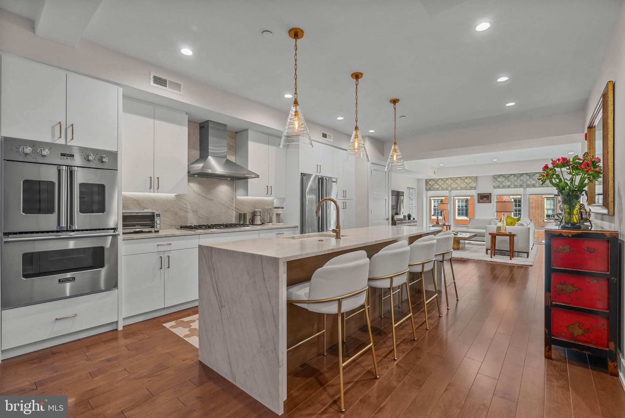 262 South 16th Street, Unit 4 Philadelphia, PA 19102 - Photo 11 of 30 a kitchen with stainless steel appliances granite countertop a stove top oven a sink a dining table and chairs with wooden floor