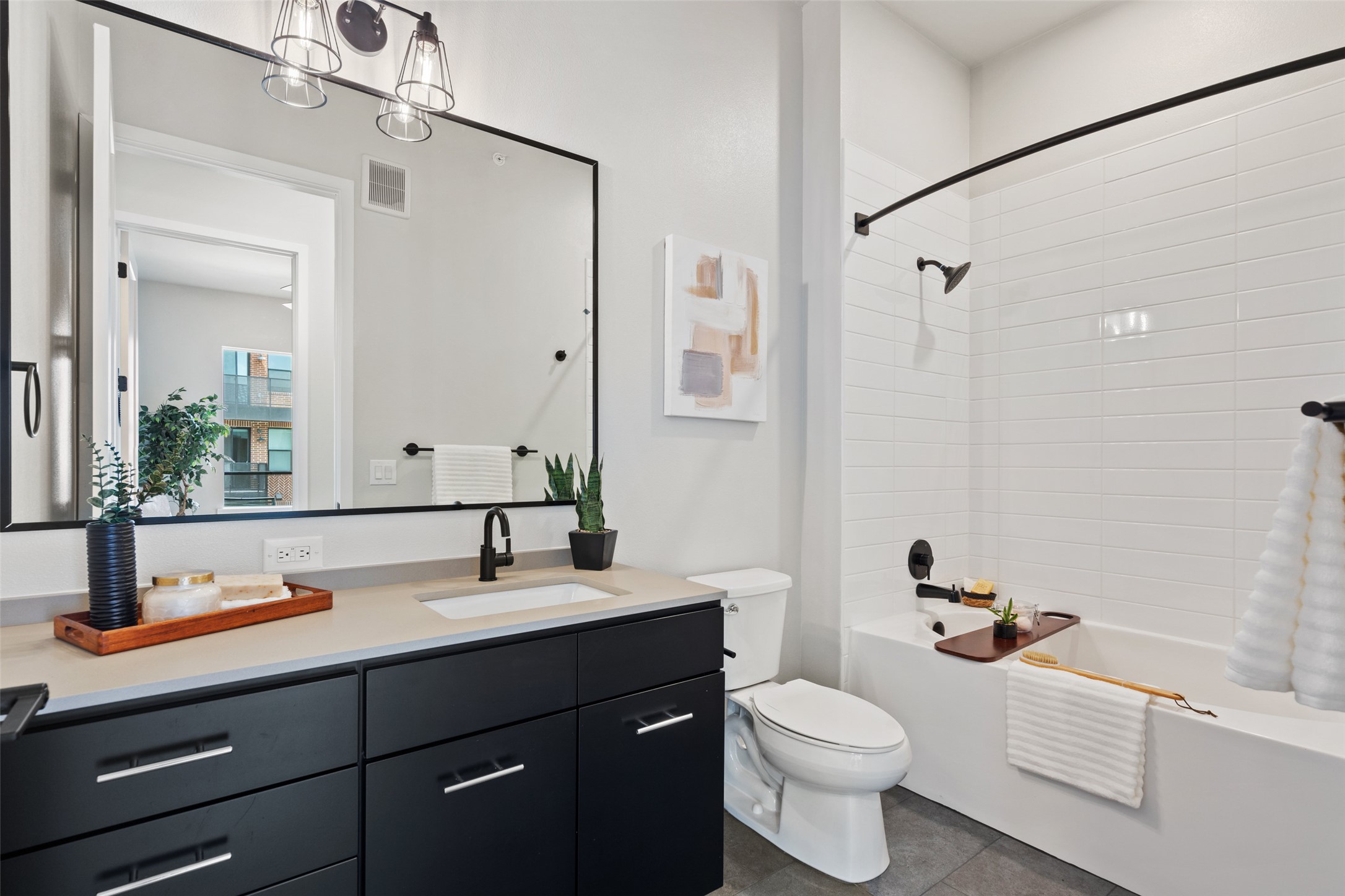 4510 Terry-O Lane, Unit 341 Austin, TX 78745 - Photo 36 of 40 Bathroom featuring a dark vanity with a light-colored countertop, a rectangular sink with a matte black faucet, and a spacious mirror with a three-light fixture