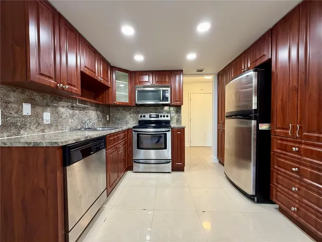a kitchen with stainless steel appliances granite countertop wooden cabinets a stove top oven a sink and dishwasher