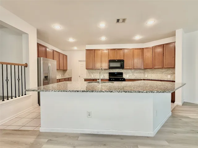 a large kitchen with granite countertop a sink a stove top oven and cabinets